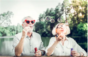 Image of two people wearing sunglasses and blowing soap bubbles.